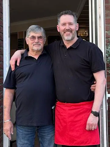 Adalberto Altoe Arm in Arm mit seinem Sohn Diego vor dem Eingang des Cafés