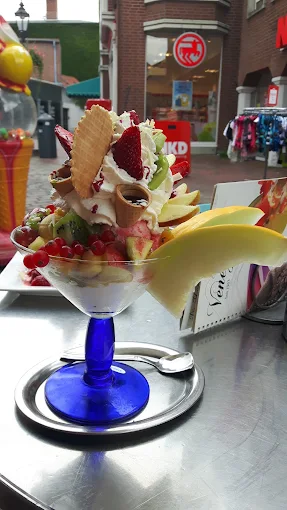 Üppiger Eisbecher mit Erdbeeren, Kiwi, Johannisbeeren, Sahne und Waffeln